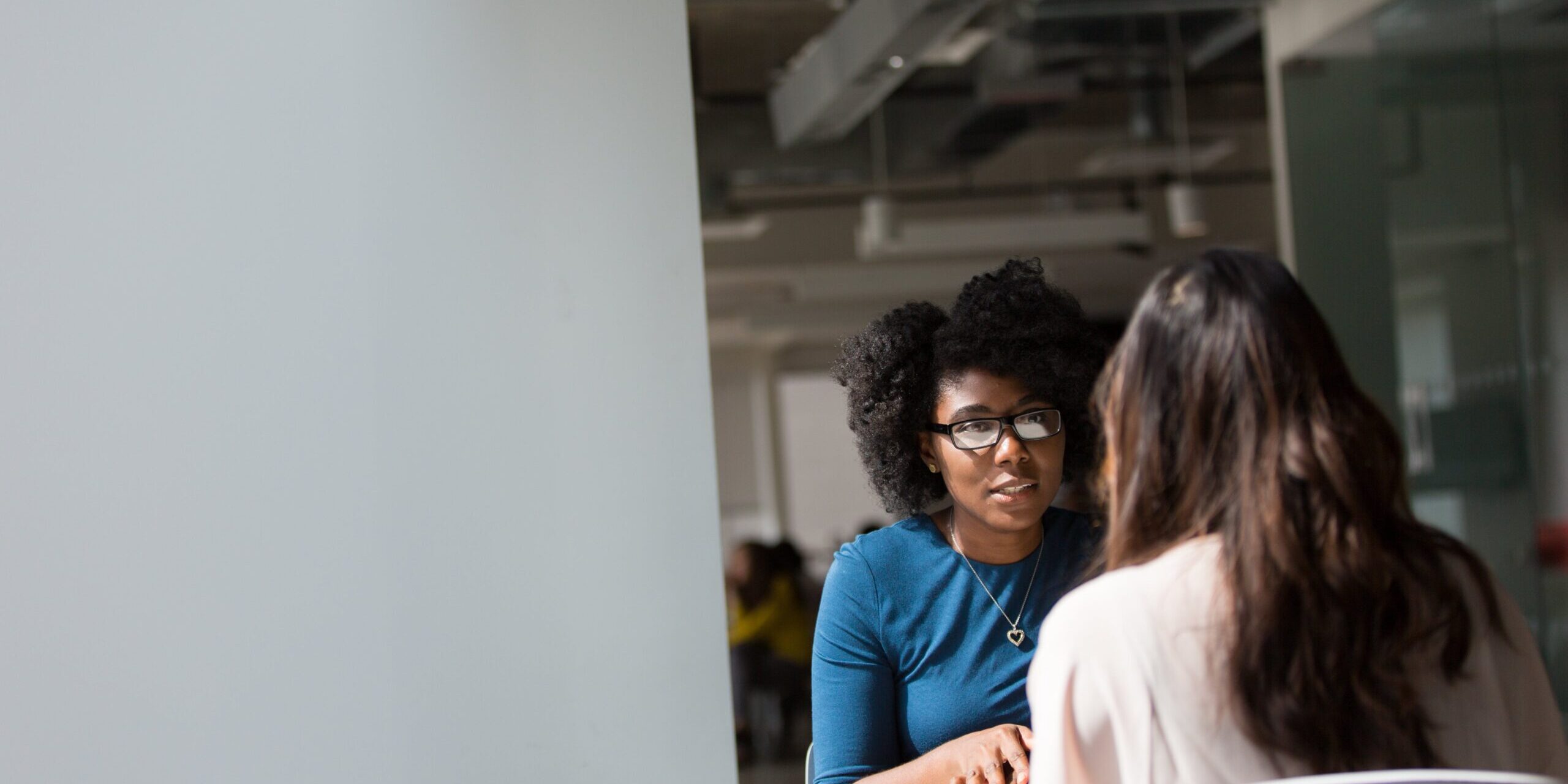 Two women sitting at a table and talking.
