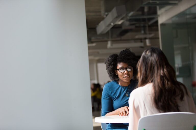 Two women sitting at a table and talking.