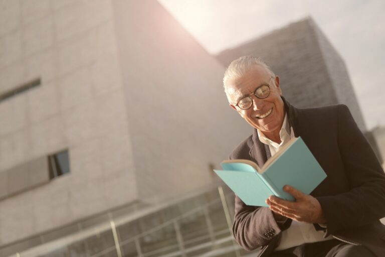 A man smiling as he reads a book.
