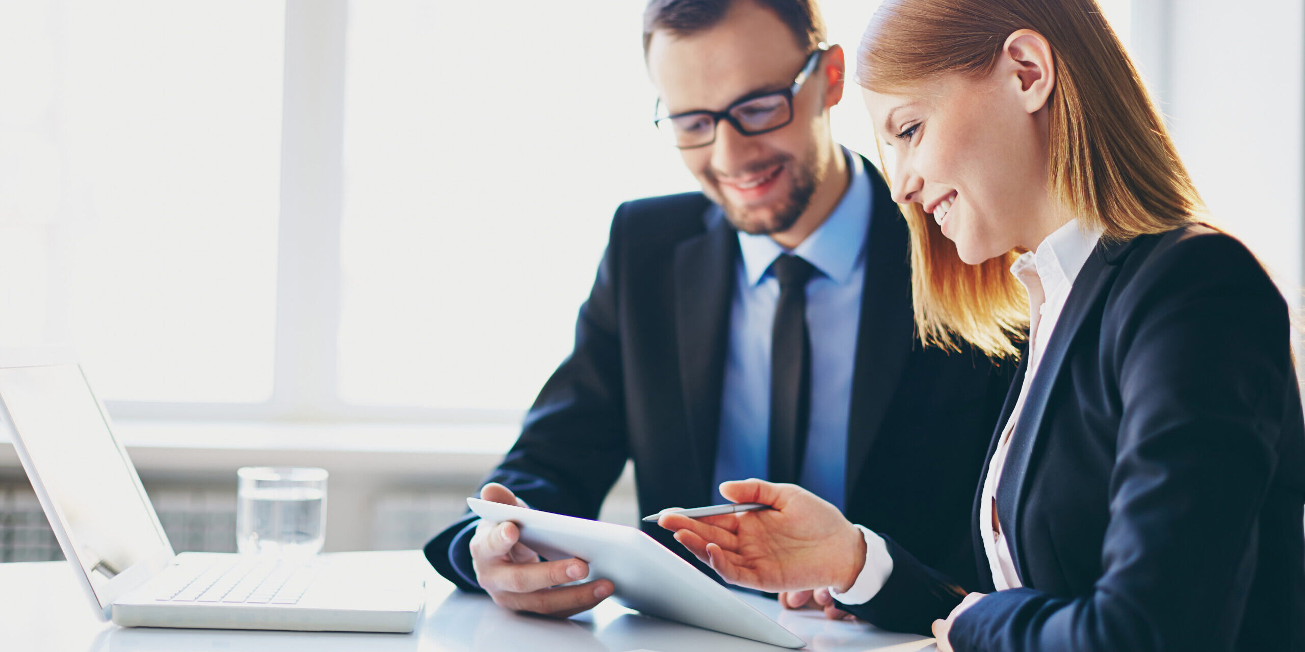 Two people in an office have a discussion and look down at a piece of paper.