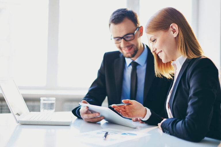 Two people in an office have a discussion and look down at a piece of paper.