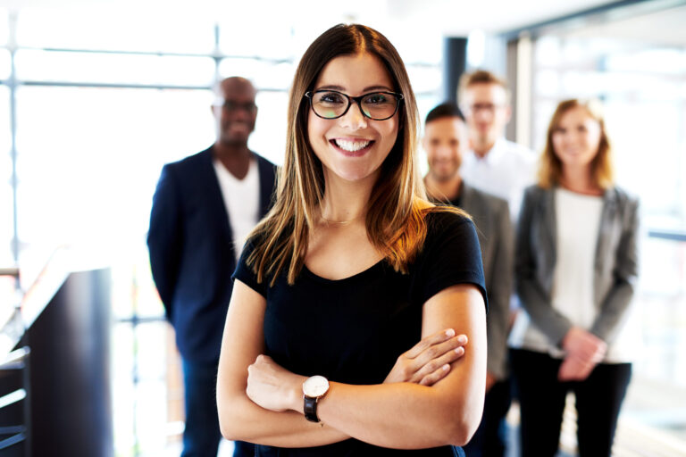 A smiling woman standing in front of a group of other people.