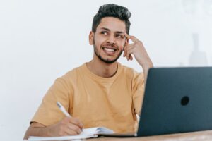 A man smiling and thinking in front of his computer. 