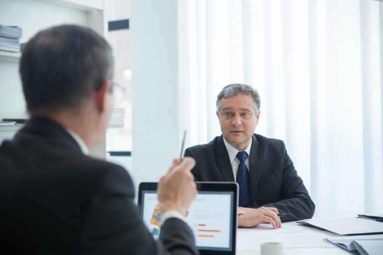 Two men on a meeting and one of them pointing at the other.