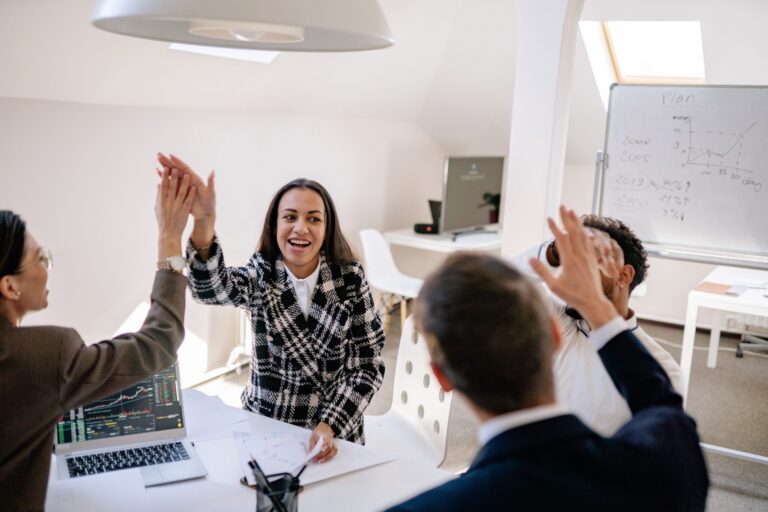 A group of people around a table celebrate and high-five one another.