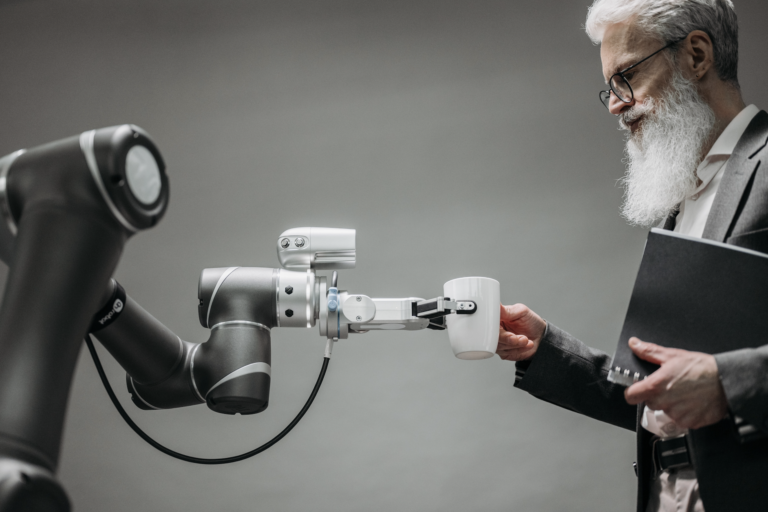 A man takes a mug from a machine, which holds the mug out towards him with a robotic limb.