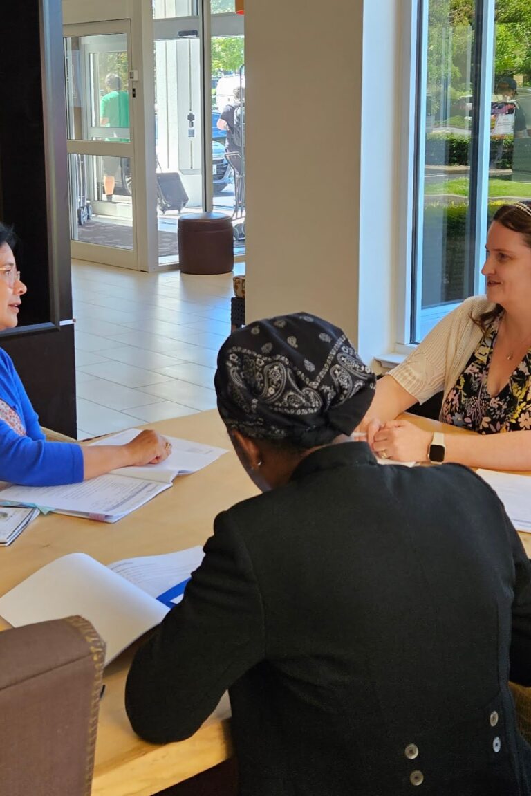 Three seminar attendees talk and refer to their notes.