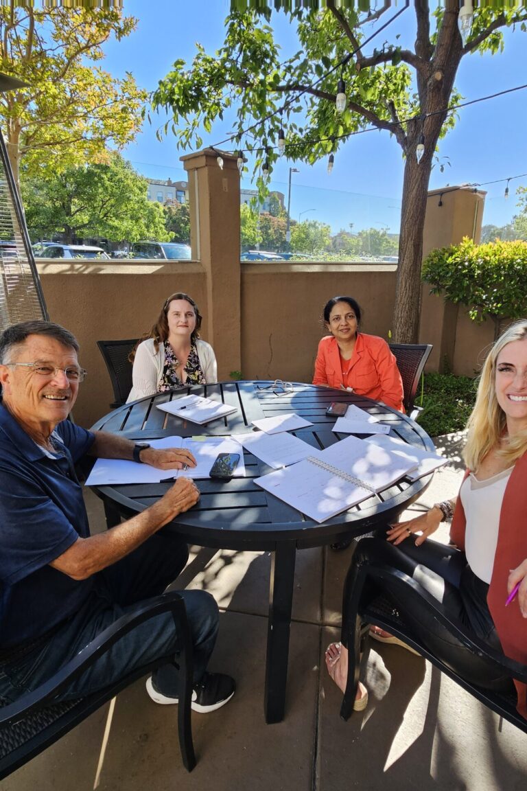Four seminar attendees seated around a table an smiling at the camera.