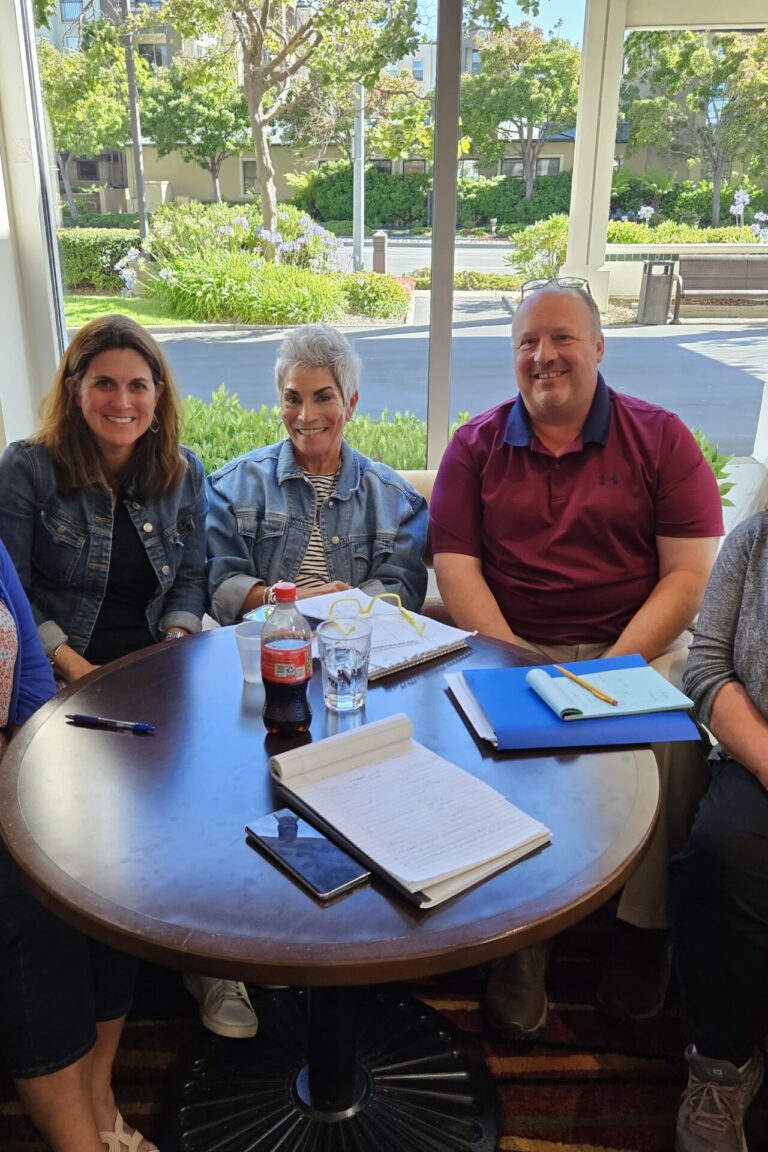 A group of seminar attendees gathered around a table and smiling at the camera.
