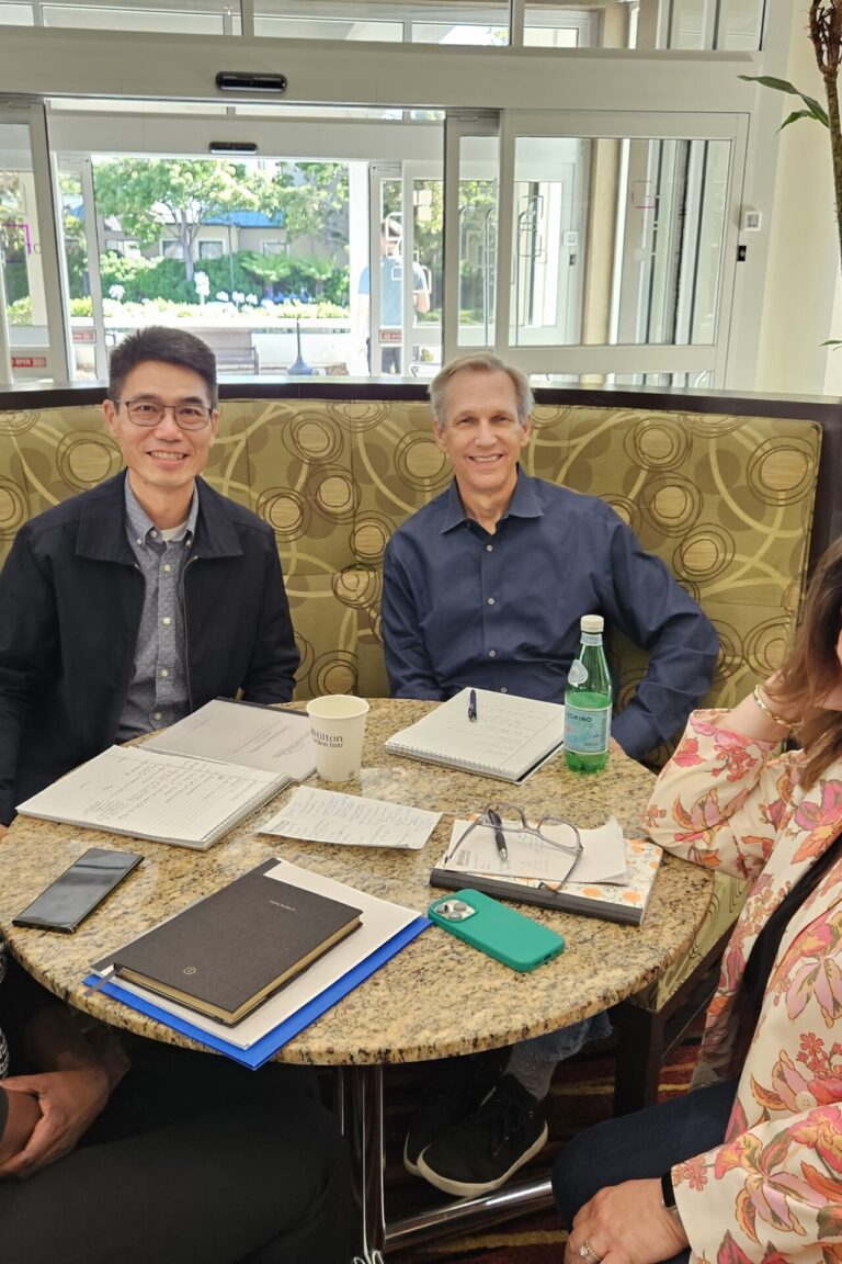 Seminar attendees gathered around a table and smiling at the camera.