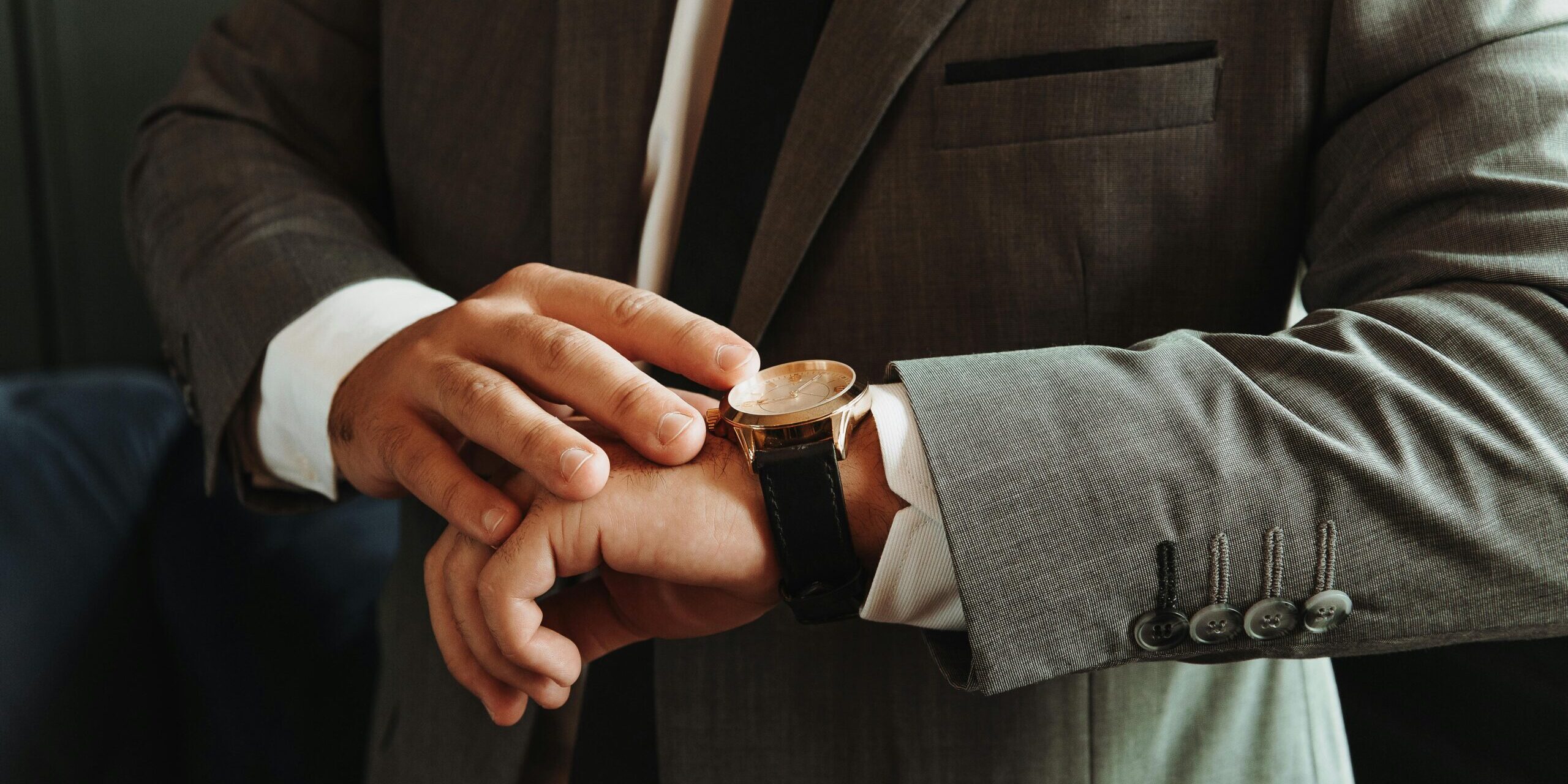A business man look at his watch to check the time.