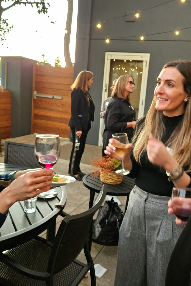 A group of seminar attendees and instructors chatting amicably and enjoying glasses of wine.